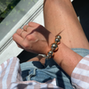 Close-up of a person's wrist wearing a gold bracelet with sunlight casting shadows.