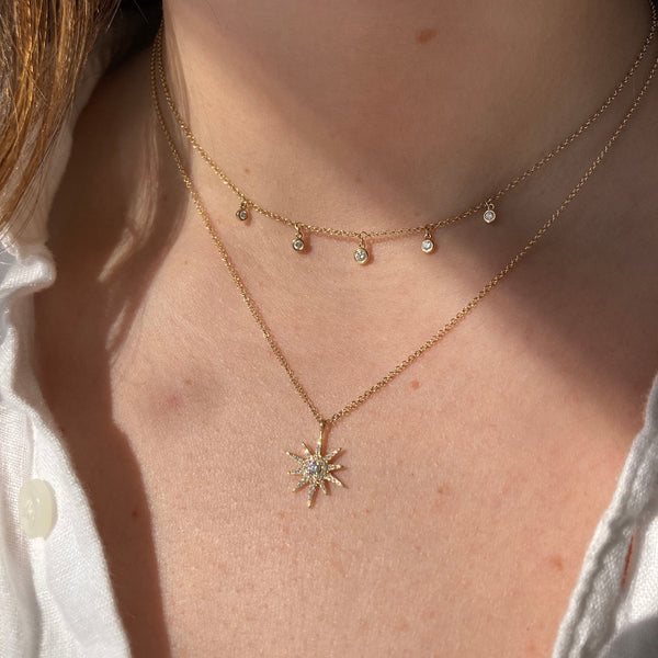 The yellow gold dew drop diamond station necklace is paired with our starburst diamond necklace.
