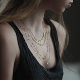 In Sia Taylor's Tiny Dots Arc Necklace hammered gold discs cascade along a gold chain.